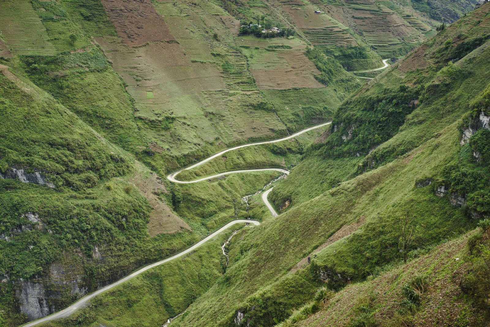 The road winding through green valleys at Mã Pí Lèng