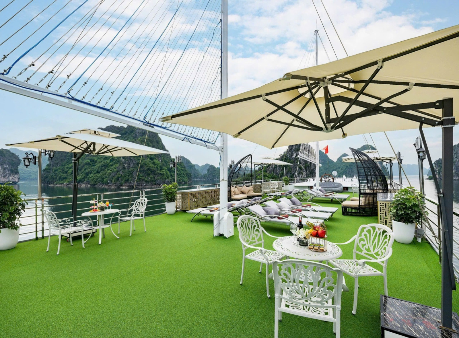 The grass sundeck with white garden chairs, parasols and loungers, islands all around
