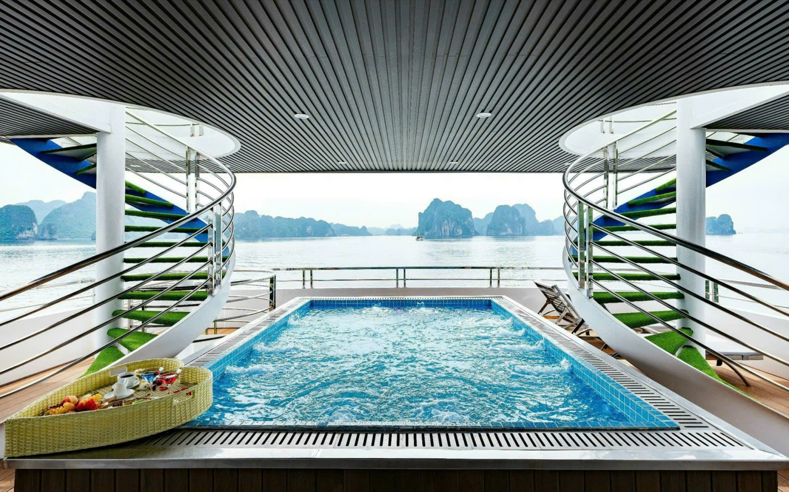 A pool at the stern between two spiral staircases, looking out over the karst islands