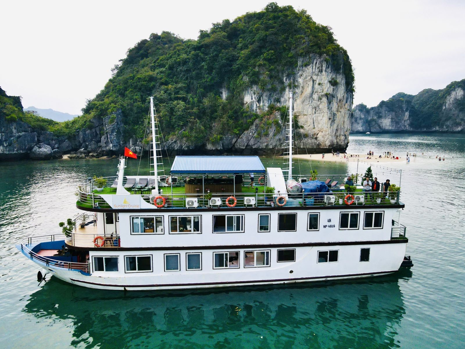 The Sunlight Premium boat anchored under a karst island, a small beach behind