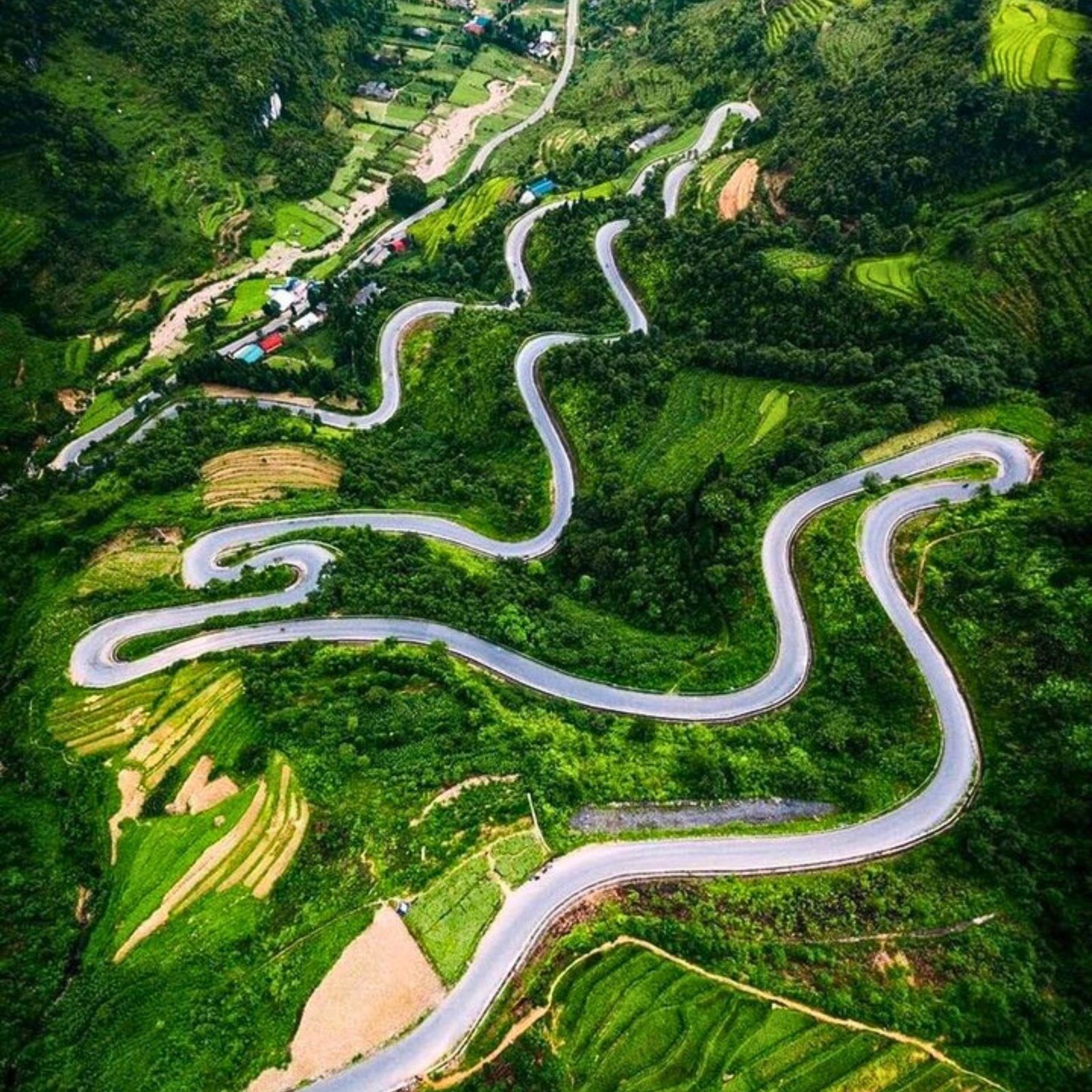 Aerial view of a pass looping back and forth through green fields and terraces