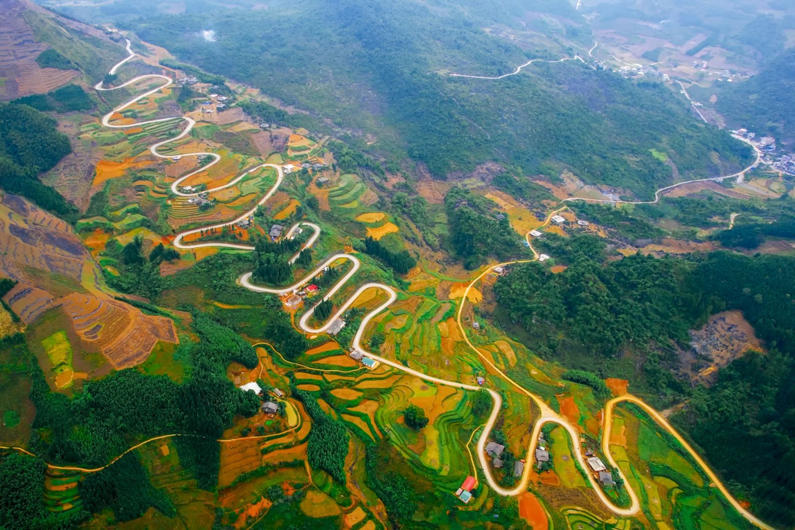 Aerial view of the Khau Cốc Chà pass zigzagging down through colourful terraces