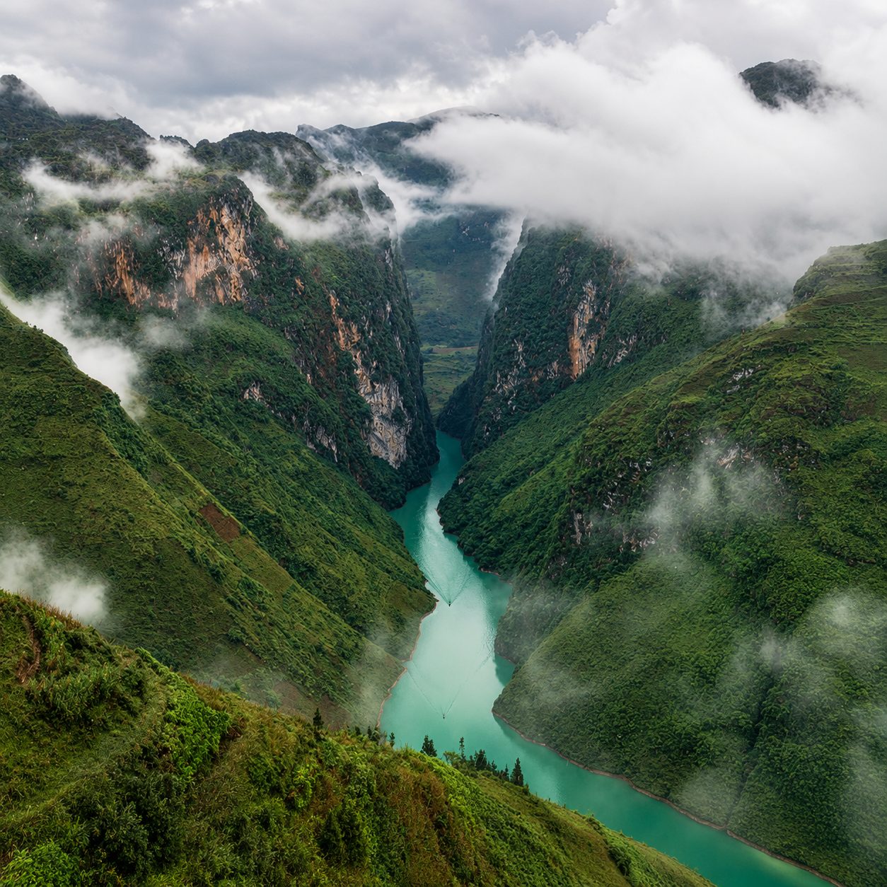 Low clouds drifting through the Nho Quế canyon, the green river far below
