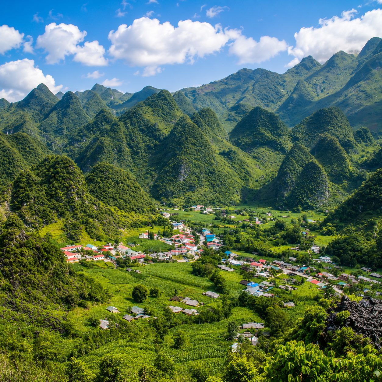 A village of bright roofs in a valley ringed by cone-shaped karst hills