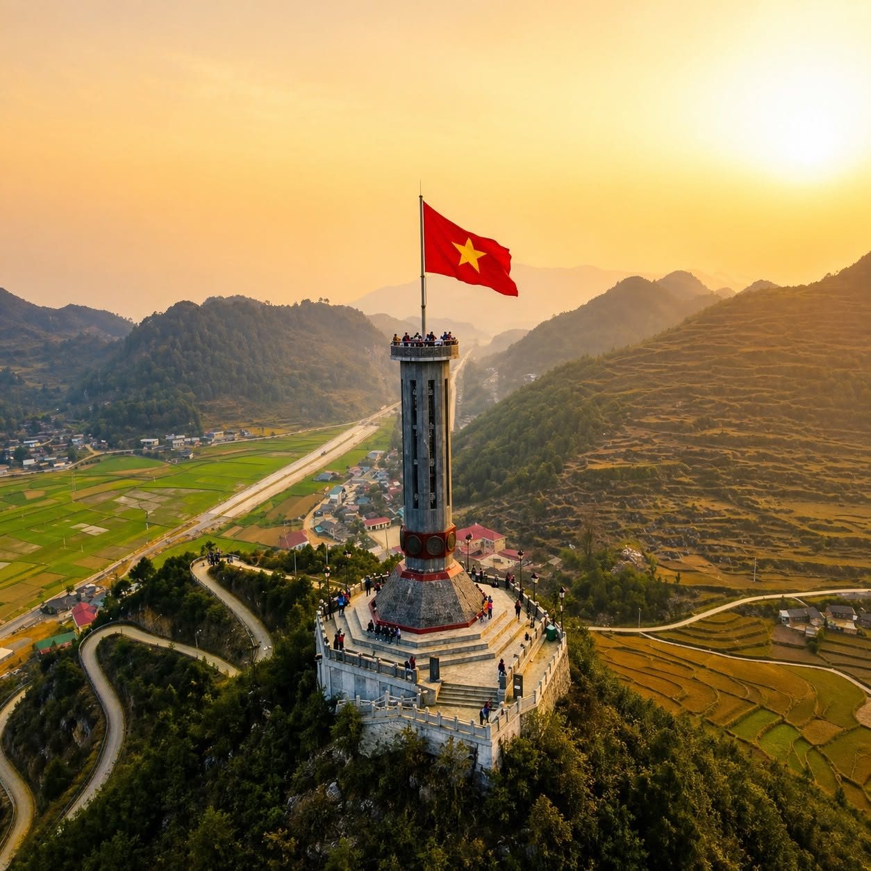 The Lũng Cú flag tower on its hilltop at sunset, roads and fields far below
