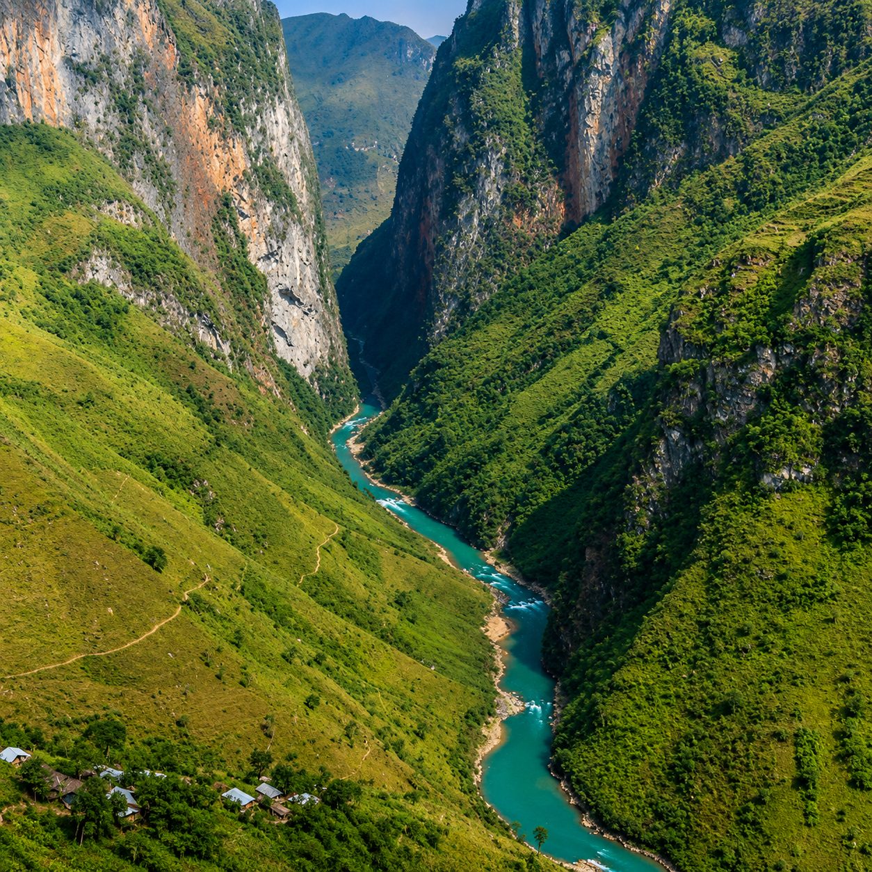 Sheer canyon walls above the narrow turquoise Nho Quế River